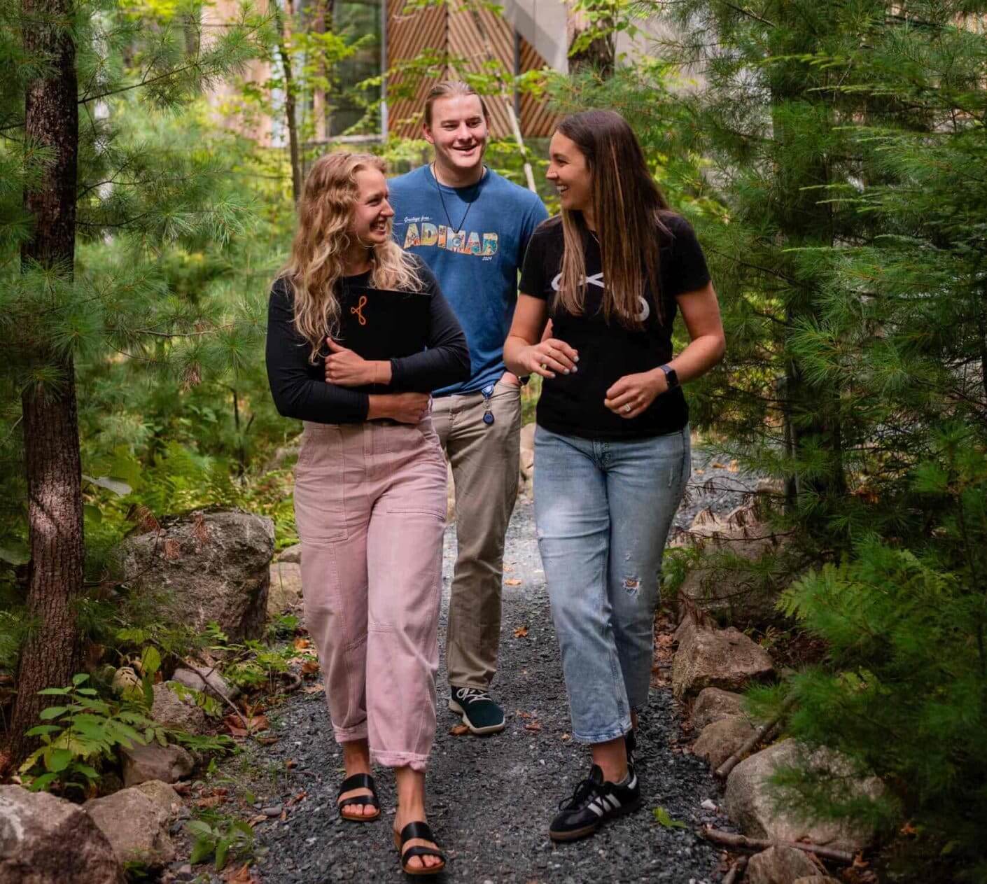 Three Adimab team members walking and talking on a wooded path outside the office.